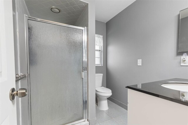 bathroom featuring a shower with shower door, toilet, vanity, and tile patterned floors