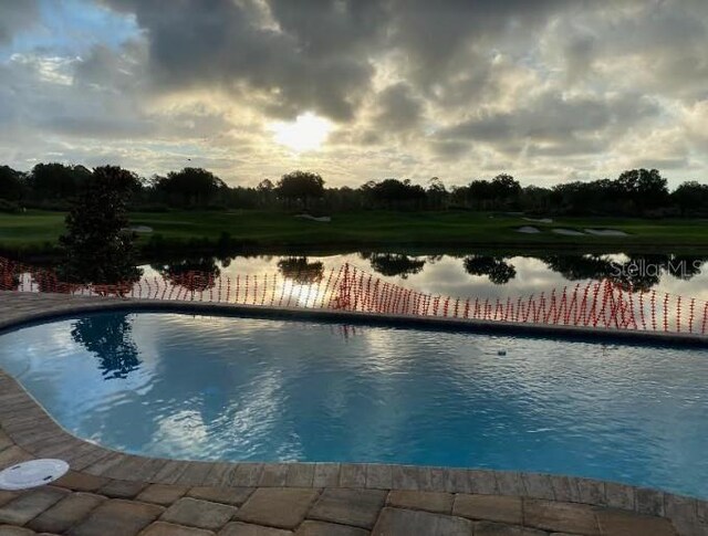 pool at dusk featuring a water view