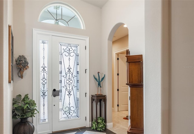 entryway with light tile patterned flooring and a high ceiling