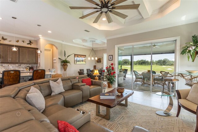 living room with ceiling fan, crown molding, a tray ceiling, and light tile patterned floors