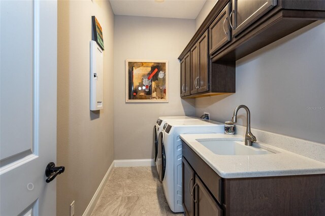 clothes washing area featuring light tile patterned flooring, sink, washing machine and dryer, and cabinets