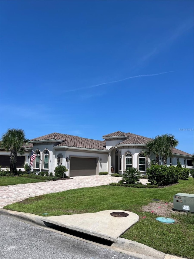 mediterranean / spanish house featuring a garage and a front lawn