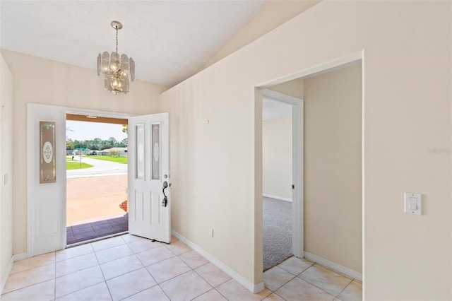 tiled foyer with lofted ceiling and a chandelier