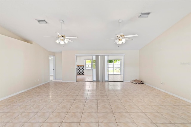 empty room with ceiling fan, lofted ceiling, and light tile patterned floors