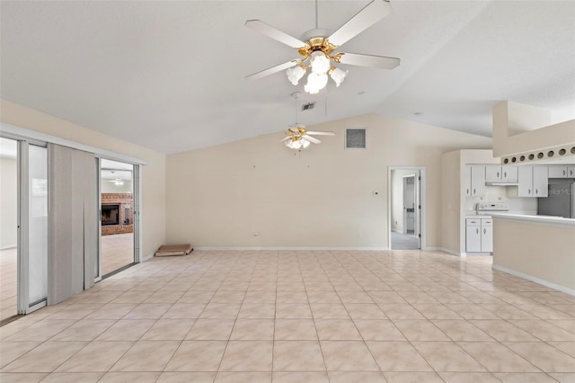 spare room featuring high vaulted ceiling, ceiling fan, light tile patterned floors, and a brick fireplace