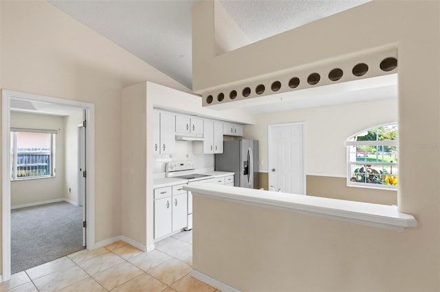 kitchen with electric stove, white cabinets, light tile patterned floors, stainless steel fridge, and vaulted ceiling