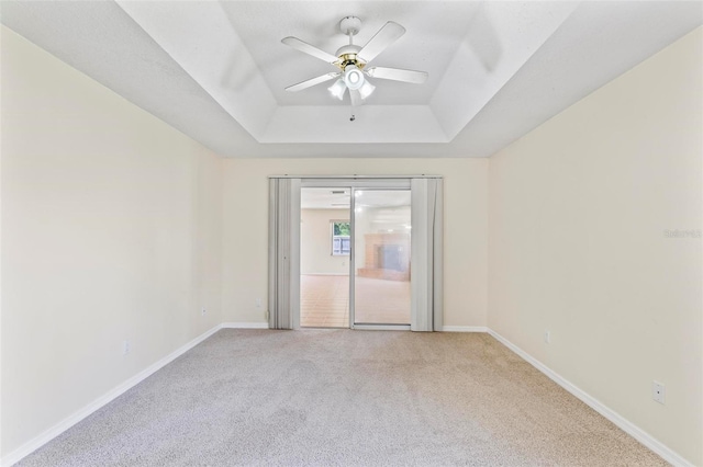 carpeted empty room with a tray ceiling and ceiling fan