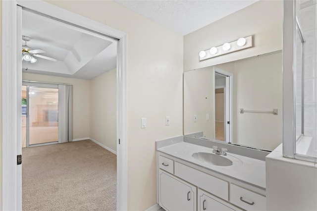 bathroom with ceiling fan, a textured ceiling, vanity, and a tray ceiling