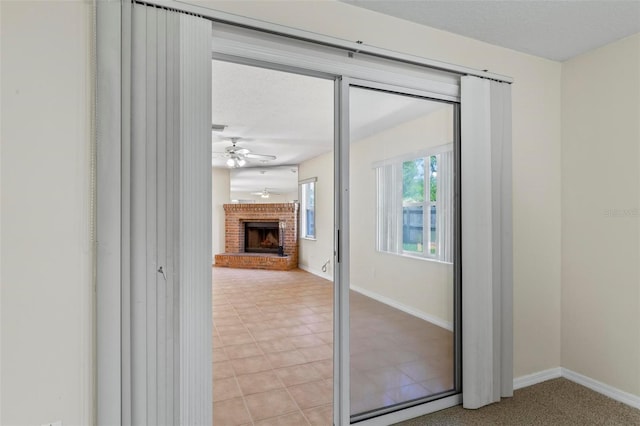 interior space featuring ceiling fan, a brick fireplace, and light tile patterned flooring