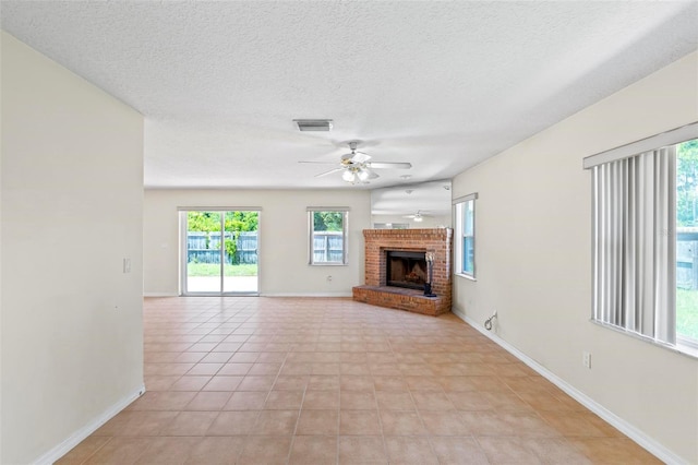 unfurnished living room featuring a textured ceiling, ceiling fan, light tile patterned floors, and a brick fireplace