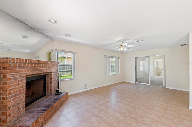 unfurnished living room with ceiling fan, a fireplace, plenty of natural light, and light tile patterned floors