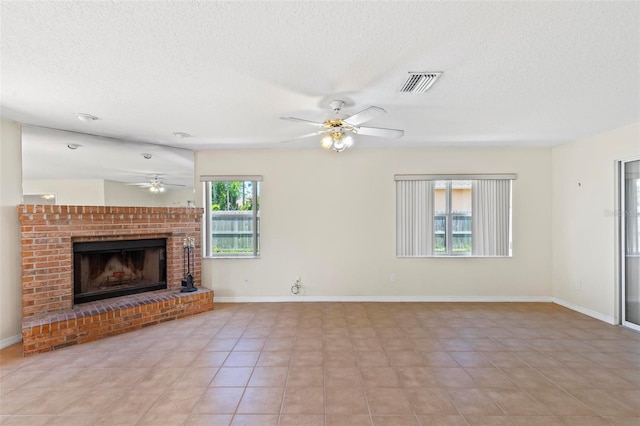 unfurnished living room featuring a textured ceiling, ceiling fan, light tile patterned floors, and a brick fireplace