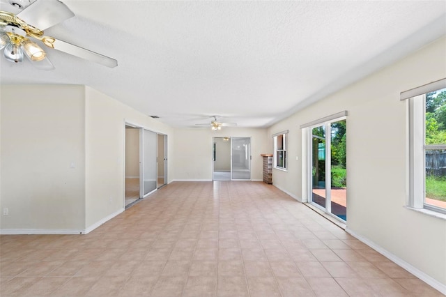 tiled spare room with ceiling fan, a wealth of natural light, and a textured ceiling