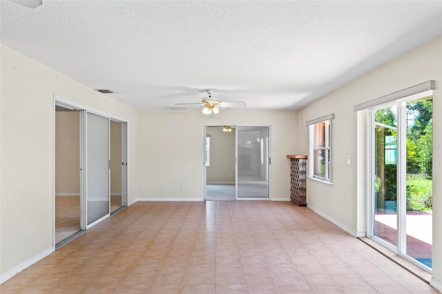 tiled spare room with a textured ceiling and ceiling fan