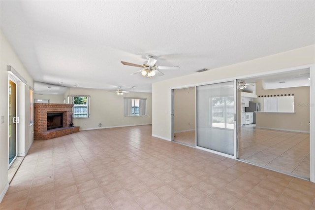 unfurnished living room featuring a textured ceiling, ceiling fan, light tile patterned floors, and a brick fireplace