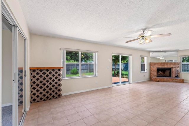 unfurnished living room featuring ceiling fan, a fireplace, a textured ceiling, and light tile patterned floors