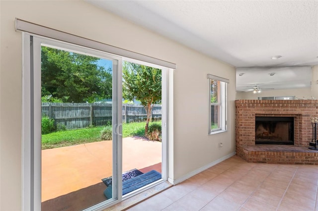 interior space with ceiling fan, a fireplace, plenty of natural light, and light tile patterned floors