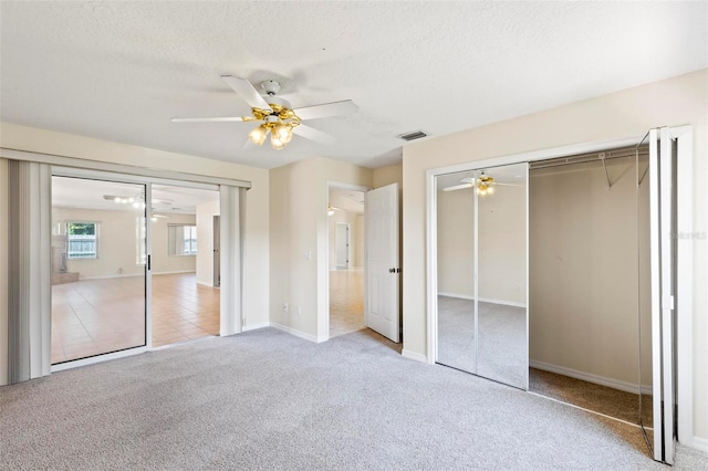 unfurnished bedroom with ceiling fan, a textured ceiling, and light carpet