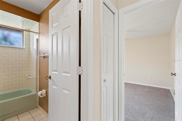 bathroom featuring tile patterned flooring, a textured ceiling, and tiled shower / bath