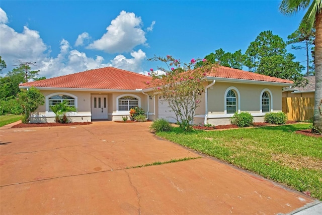 mediterranean / spanish-style house with a garage and a front lawn