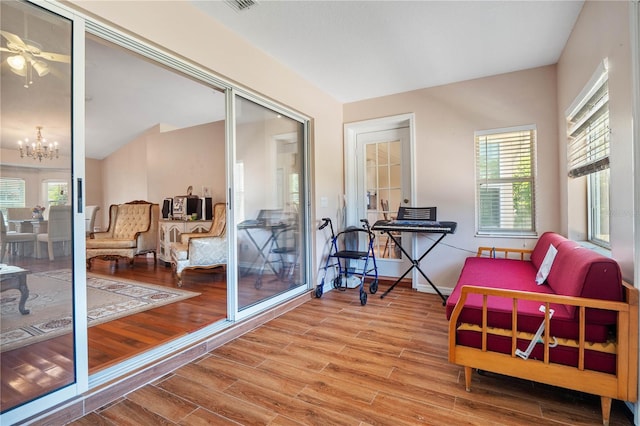 sitting room with lofted ceiling, a notable chandelier, and hardwood / wood-style floors