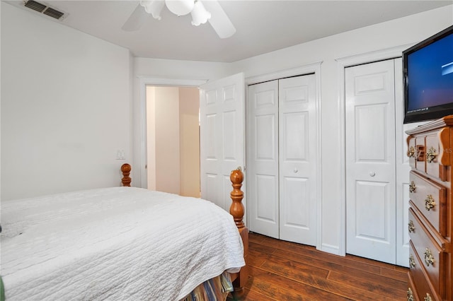 bedroom featuring dark wood-type flooring, two closets, and ceiling fan