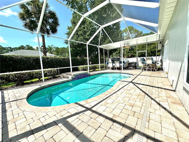 view of pool with outdoor lounge area, ceiling fan, a patio area, and a lanai