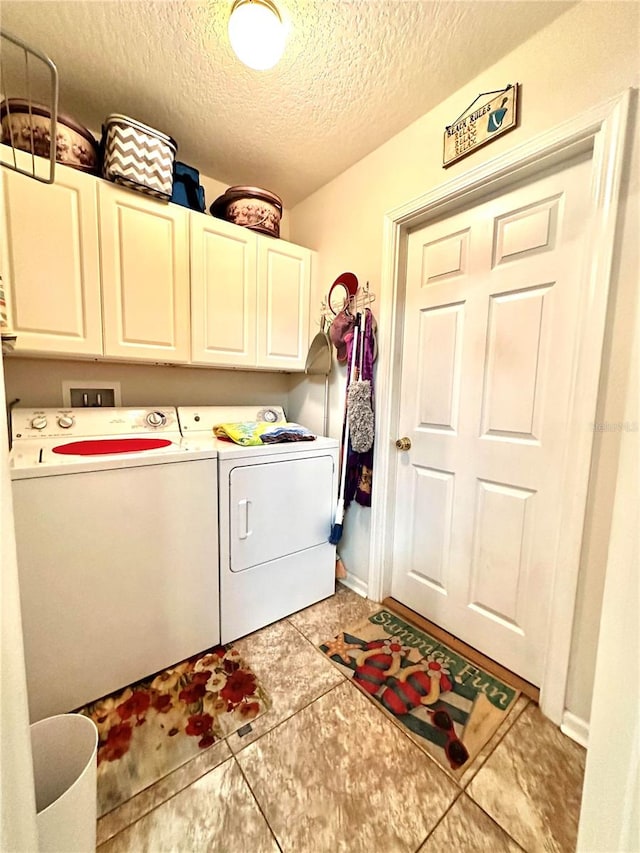 washroom with cabinets, light tile patterned floors, a textured ceiling, and washing machine and clothes dryer