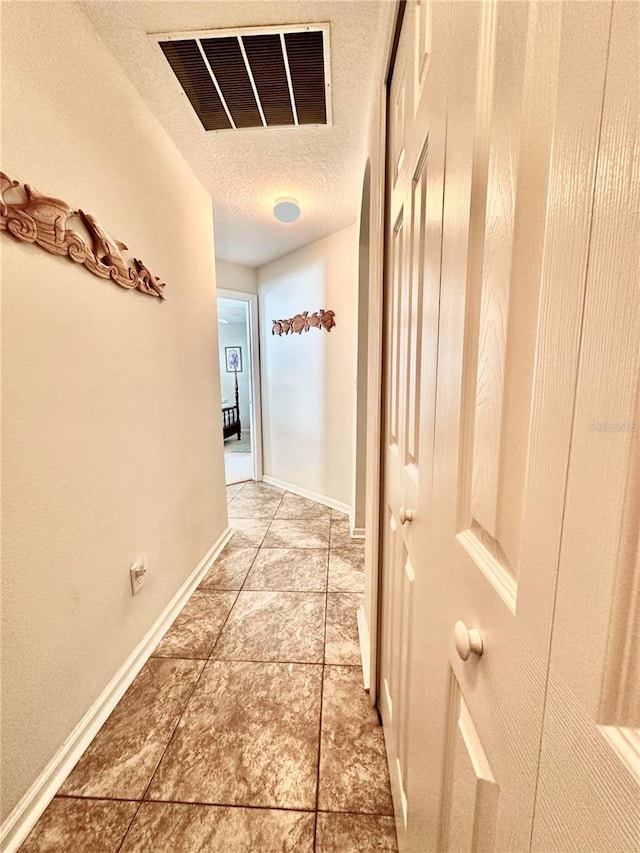 hallway featuring a textured ceiling and tile patterned floors