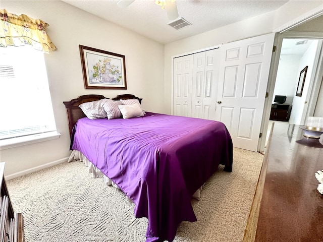 bedroom with ceiling fan, light colored carpet, a textured ceiling, and a closet