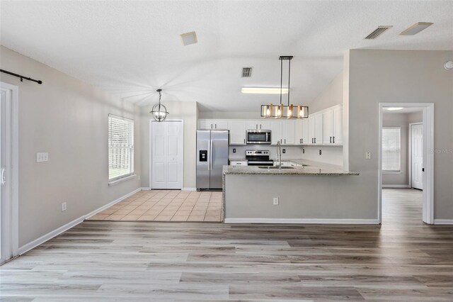 kitchen featuring stainless steel appliances, light stone counters, white cabinets, kitchen peninsula, and light tile patterned flooring