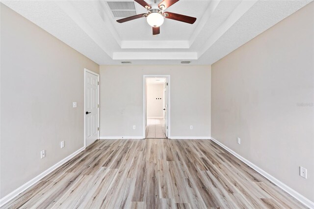 tiled empty room featuring ceiling fan and a raised ceiling