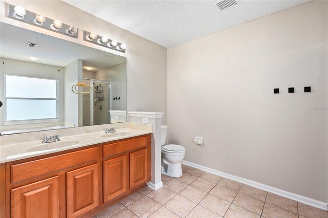 bathroom featuring tile patterned flooring, toilet, vanity, and walk in shower