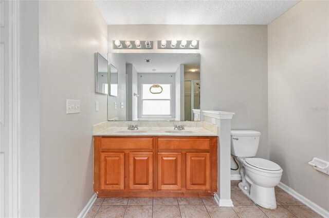 bathroom featuring tile patterned flooring, a textured ceiling, vanity, and toilet