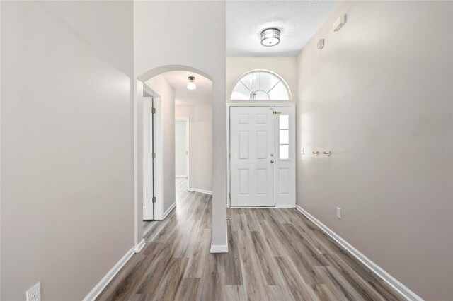 entryway featuring a high ceiling, wood-type flooring, and a textured ceiling