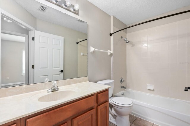 full bathroom featuring toilet, tile patterned flooring, vanity, a textured ceiling, and tiled shower / bath combo