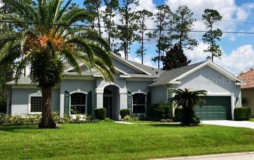 single story home with stucco siding, a front yard, concrete driveway, and a garage