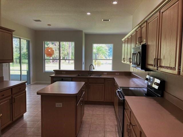 kitchen featuring light tile patterned flooring, a kitchen island, a textured ceiling, sink, and electric range