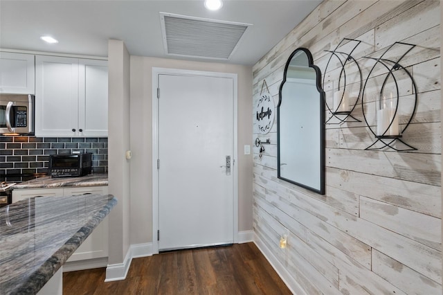 interior space with wooden walls and dark hardwood / wood-style floors