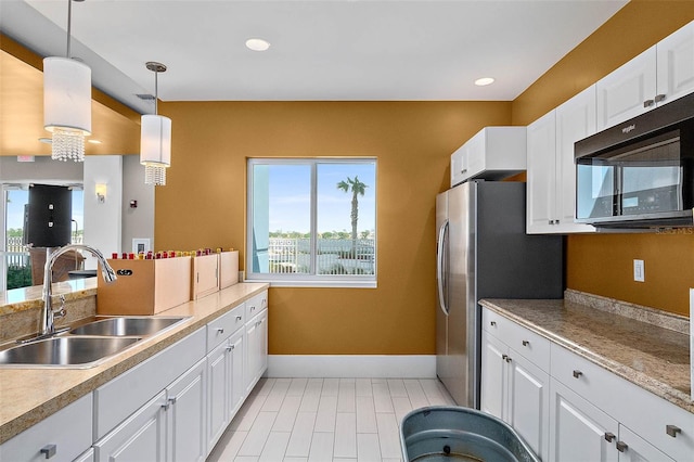 kitchen featuring sink, white cabinets, hanging light fixtures, and a healthy amount of sunlight