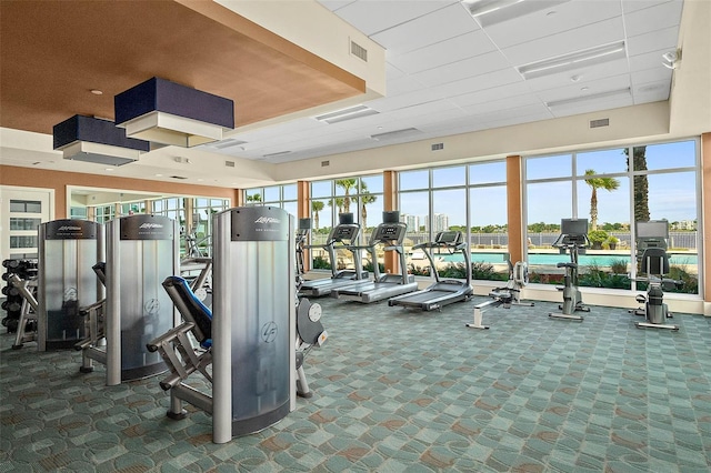 exercise room featuring dark colored carpet and a paneled ceiling