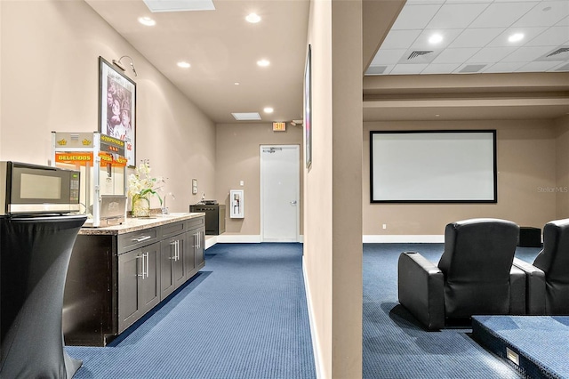 cinema featuring dark colored carpet and a paneled ceiling