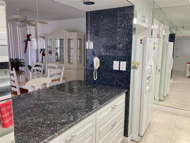 kitchen with freestanding refrigerator, white refrigerator with ice dispenser, white cabinets, and light tile patterned floors