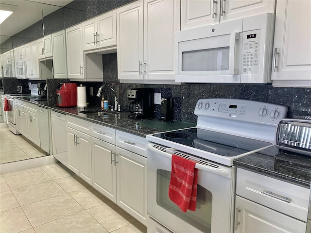 kitchen featuring light tile patterned flooring, white appliances, a sink, white cabinetry, and backsplash