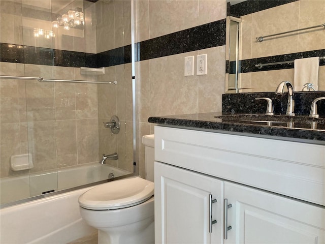 bathroom with toilet, shower / bath combination with glass door, tile walls, and vanity