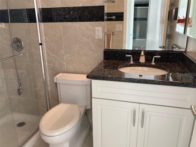 full bathroom with a stall shower, toilet, tile walls, and vanity