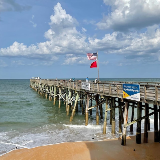 dock area with a pier, a water view, and a beach view