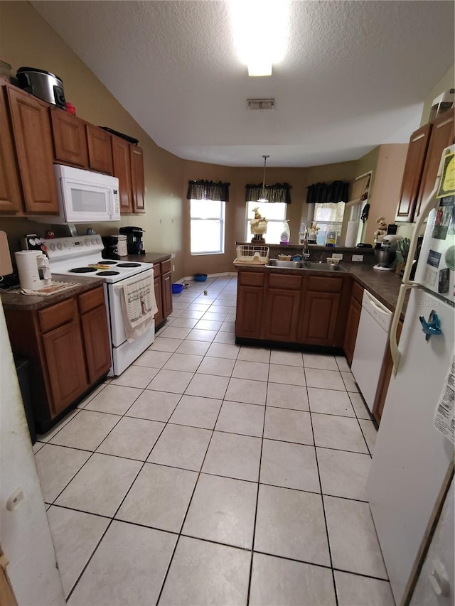 kitchen with kitchen peninsula, a textured ceiling, white appliances, light tile patterned floors, and decorative light fixtures