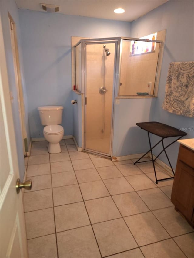 bathroom with tile patterned floors, a shower with door, vanity, and toilet