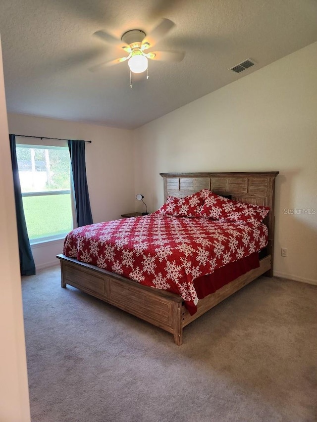 bedroom featuring ceiling fan, carpet flooring, and a textured ceiling